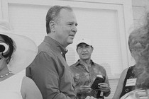 Black-and-white photo of Adam Schiff shaking hands with a person, surrounded by others