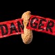 a peanut breaks through red "danger" tape against a black background