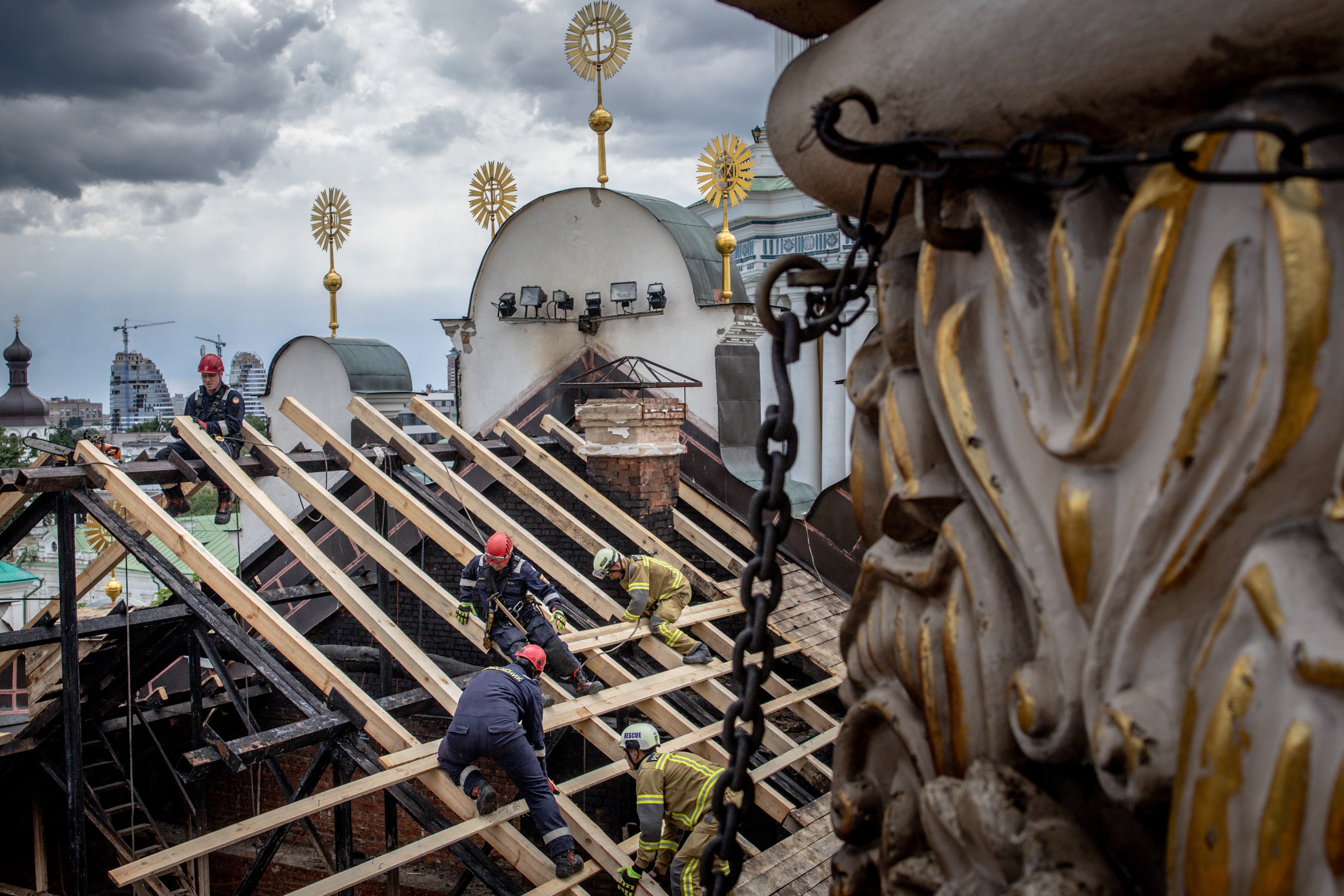 People work to repair the burned and damaged roof of a historic cathedral.