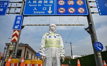 A police officer in protective gear stands in front of a road-tunnel entrance, beneath street signs.