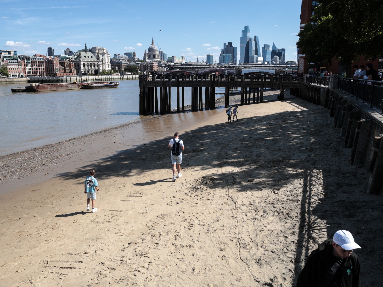 People walk on a beach on the south bank of Thames River in central London.