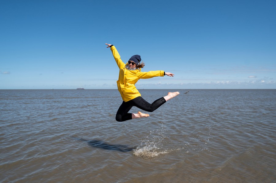 A person jumps in shallow water at the beach.