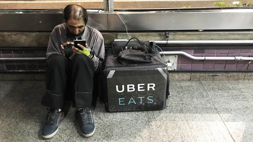 An Uber Eats worker checks his mobile phone in São Paulo.