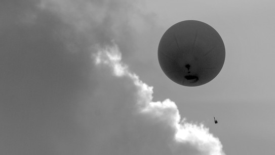 A black-and-white photo of a high-altitude weather balloon, as seen from below.