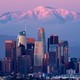 A view of the downtown Los Angeles skyline with a view of mountains in the background at sunset