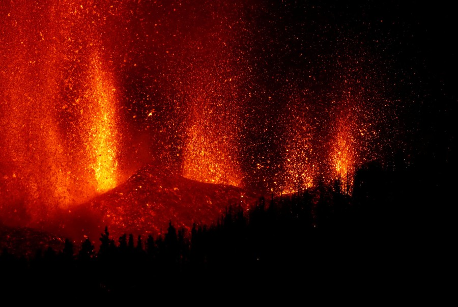 Lava flies in the air during an eruption at night.
