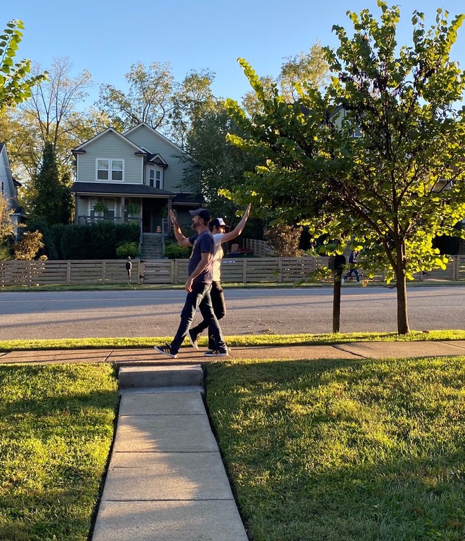 Two men mid-high five, walking past each other on the sidewalk