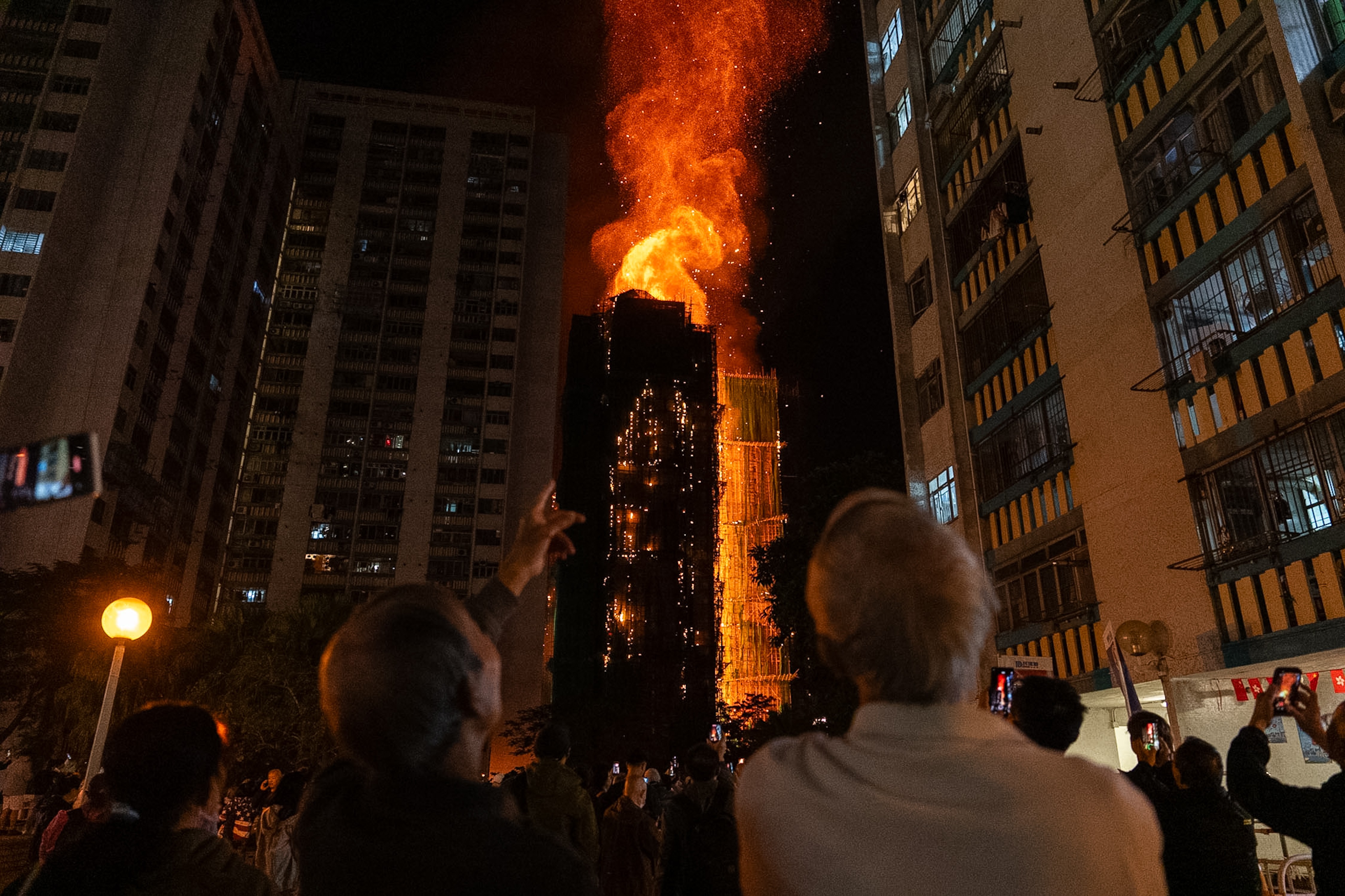 People look at flames engulfing a building complex in Hong Kong.