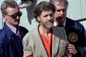 A photograph of Theodore “Ted” Kaczynski is flanked by federal agents as he is led to a car from the federal courthouse in Helena, Montana, April 4, 1996