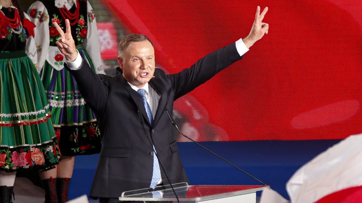 The newly reelected president of Poland, Andrzej Duda, holds his hands up in victory