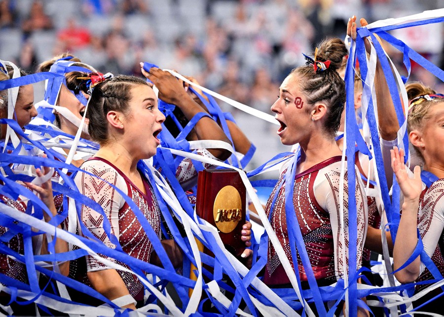 College gymnasts celebrate among blue and white streamers.