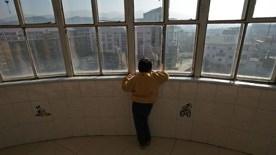 A child with autism looks out a window at the Xining Orphan and Disabled Children Welfare Center, in China.