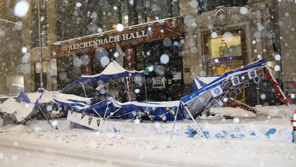 An outdoor dining tent is seen crumpled on the sidewalk during a snowstorm
