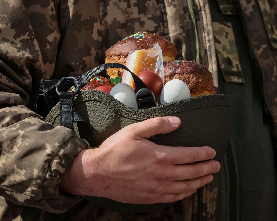 A soldier holds a helmet upside down. It is filled with eggs and pieces of cake.