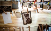 Old photographs hang from clothespins on lines on inside a gymnasium.