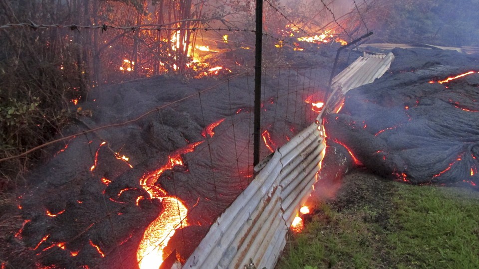 The lava flow from the Kilauea volcano moves over a fence on private property near the village of Pahoa, Hawaii, in 2014. 
