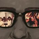 A custom image of a face with glasses; an image of a classroom is seen in one lens, and of soldiers at war in the other.  