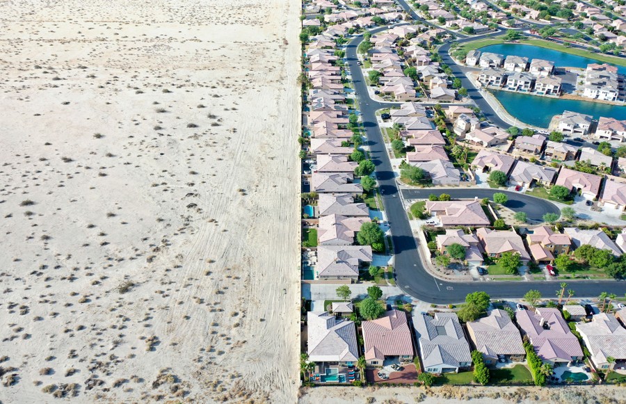 An aerial view of a housing development beside undeveloped desert, showing a striking difference in water usage.