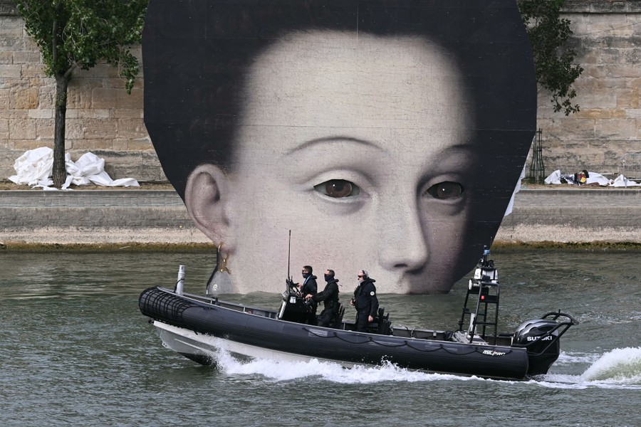 Three security officers patrol a river in a Zodiac, passing by a large decorative panel that shows a face detail from an oil painting.