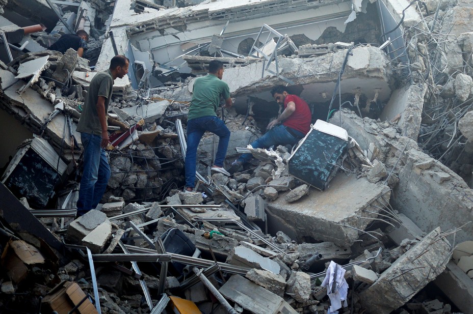 Picture of Palestinians searching for belongings in the rubble of the Watan Tower, which was destroyed in Israeli strikes, in Gaza City October 8, 2023. REUTERS/Mohammed Salem