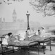 Three men sit in outdoor hospital beds with Westminster Palace in the background.