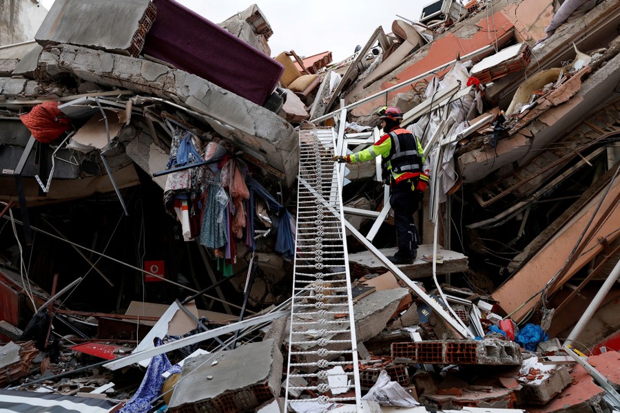 A rescue worker stands on debris from a collapsed building.