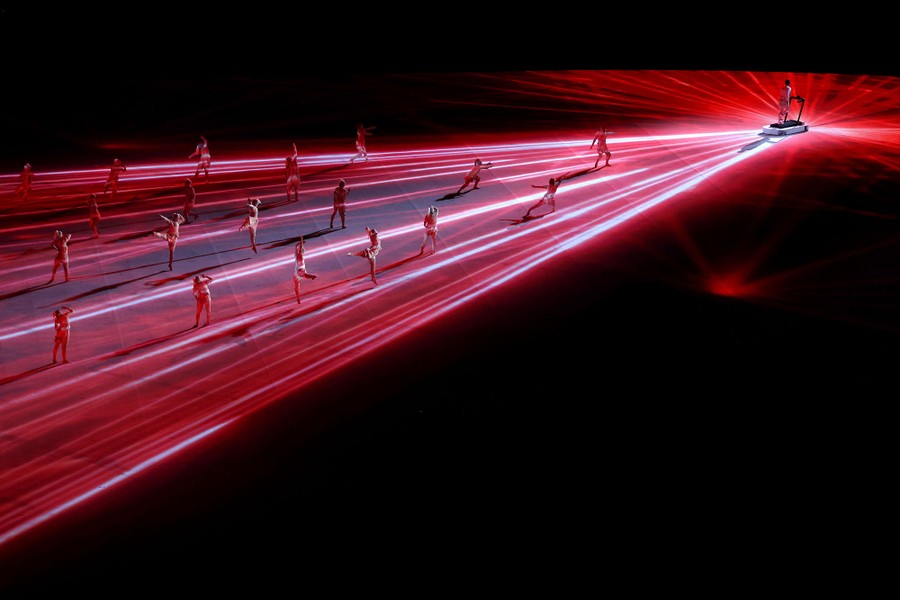 Performers dance on a broad stage amid colored lights.