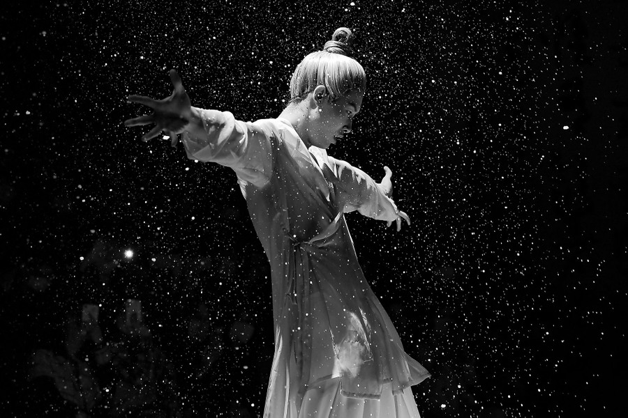 A model walks on a runway among falling particles.