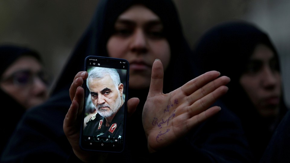 An Iranian woman displays an image of Qassem Soleimani on her phone.