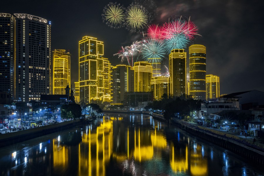 Fireworks explode over city buildings.