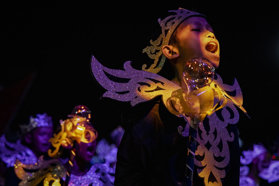 Several people in colorful illuminated costumes march in a parade.