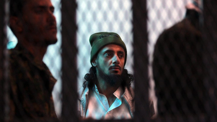 A suspected al-Qaeda militant stands behind bars.