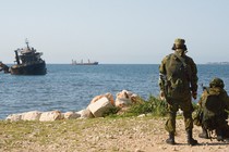 Soldiers point guns at the ocean