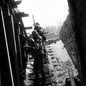 black-and-white photo of soldiers aiming weapons, descending open staircase in snow with sky behind