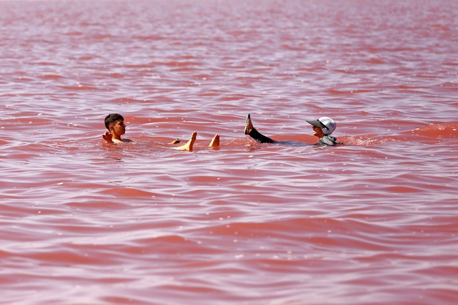 Two people float in rose-colored lake water.