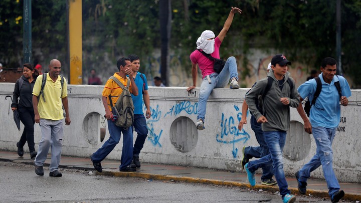 People move to cover as demonstrators rally against Venezuela's President Nicolas Maduro's government in Caracas, Venezuela, on June 28, 2017.