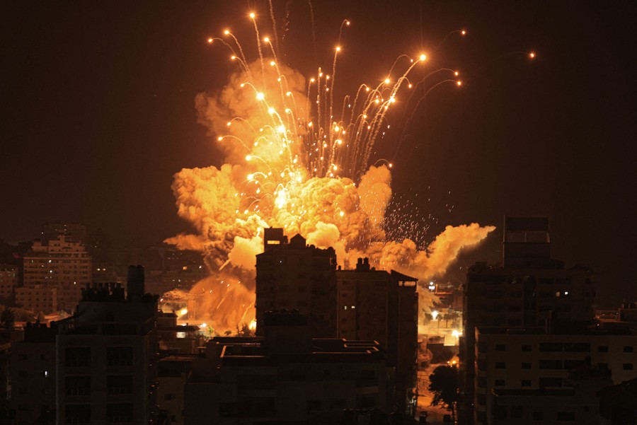 Smoke, dirt, and sparks erupt after an air strike among buildings in Gaza, seen at night.
