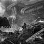 Photo of firefighter sitting on twisted metal wreckage surrounded by enormous excavators