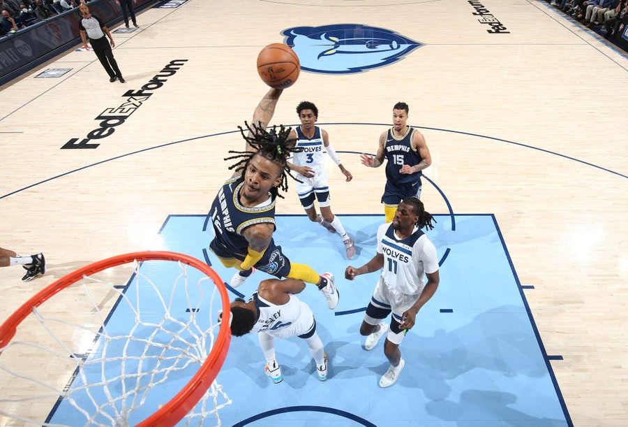 A basketball player jumps over an opponent on his way to dunk the ball.
