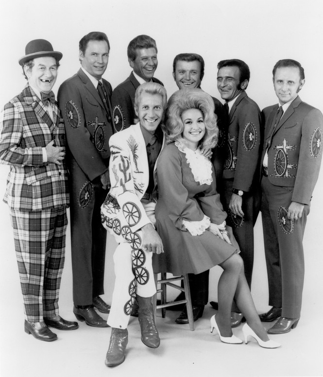 Country singers and collaborators Porter Wagoner and Dolly Parton pose for a portrait with their back up band, "The Wagonmasters", in circa 1968. Mr. Wagoner is wearing a Nudie Suit designed by Nudie Cohn of Nudie's Rodeo Tailors.