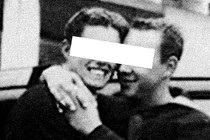 A grainy black-and-white image of two men embracing with a white rectangle covering their eyes