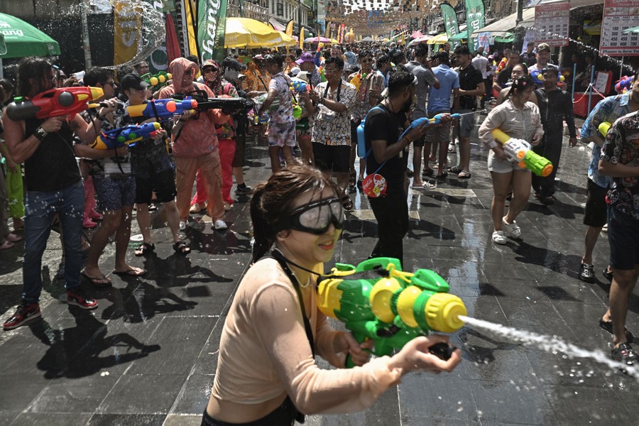 People hold water guns and spray water at each other.