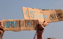 An image of a protest sign that reads "1.5 degrees to stay alive."