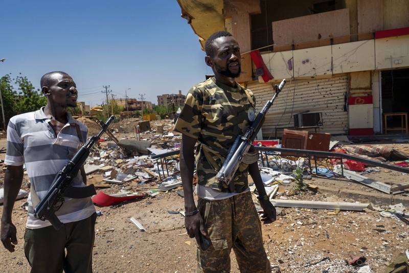 Two solders stand with guns amidst wreckage