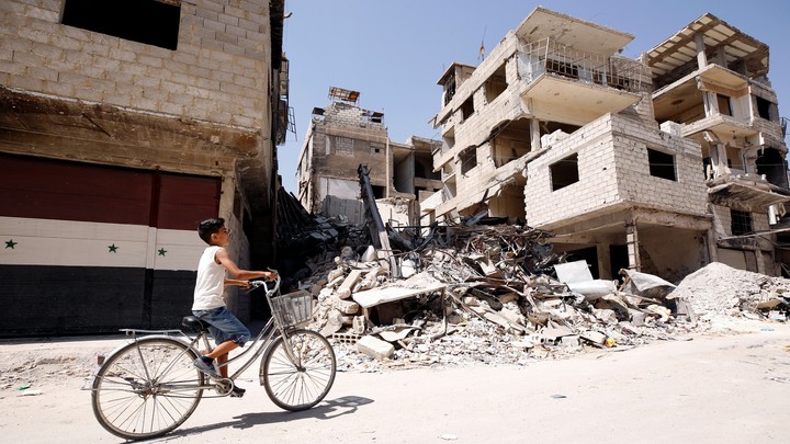 A boy rides on a bicycle in the town of Kafr Batna, in eastern Ghouta, Syria on September 5, 2018.
