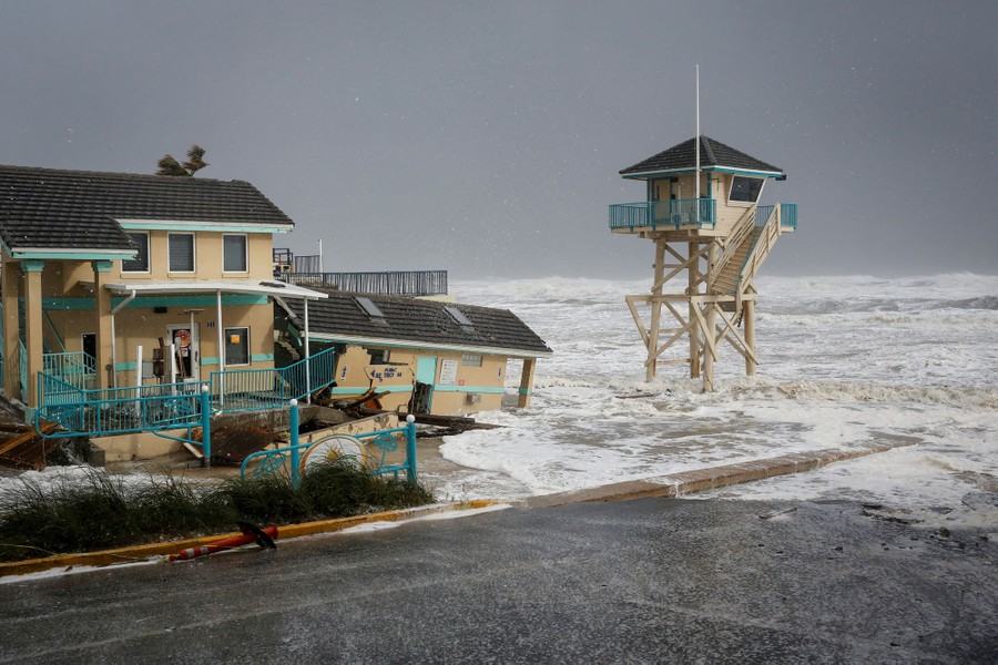 A tower and storm-damaged building are hit by waves.