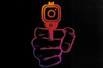 A hand pointing a gun whose muzzle is shaped like the Instagram logo