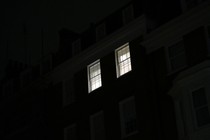 Two lit windows in a home, as seen from across the street