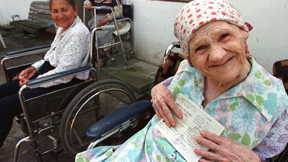 An elderly woman holds her birth certificate at a retirement home.