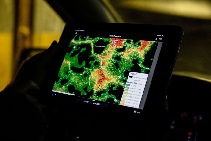 A person holds a device with a screen showing a brightly-colored map.